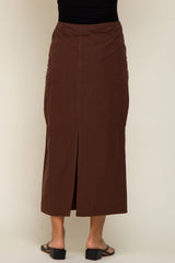 back view of a woman wearing a long brown cargo maxi skirt with a center slit and side pockets