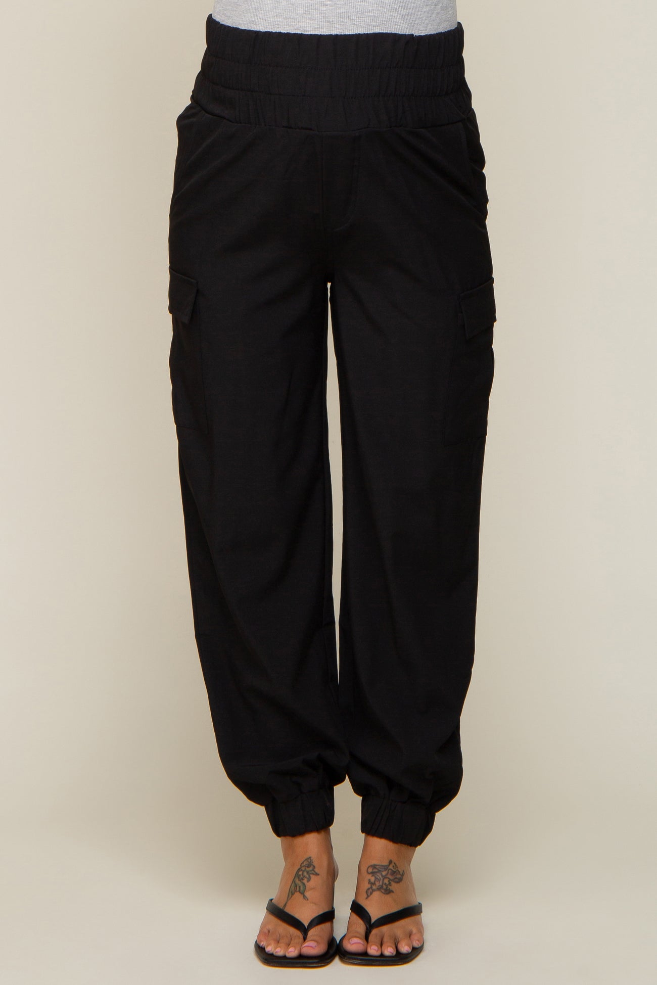 woman wearing black maternity cargo pants with an elastic waistband and tapered ankle cuffs