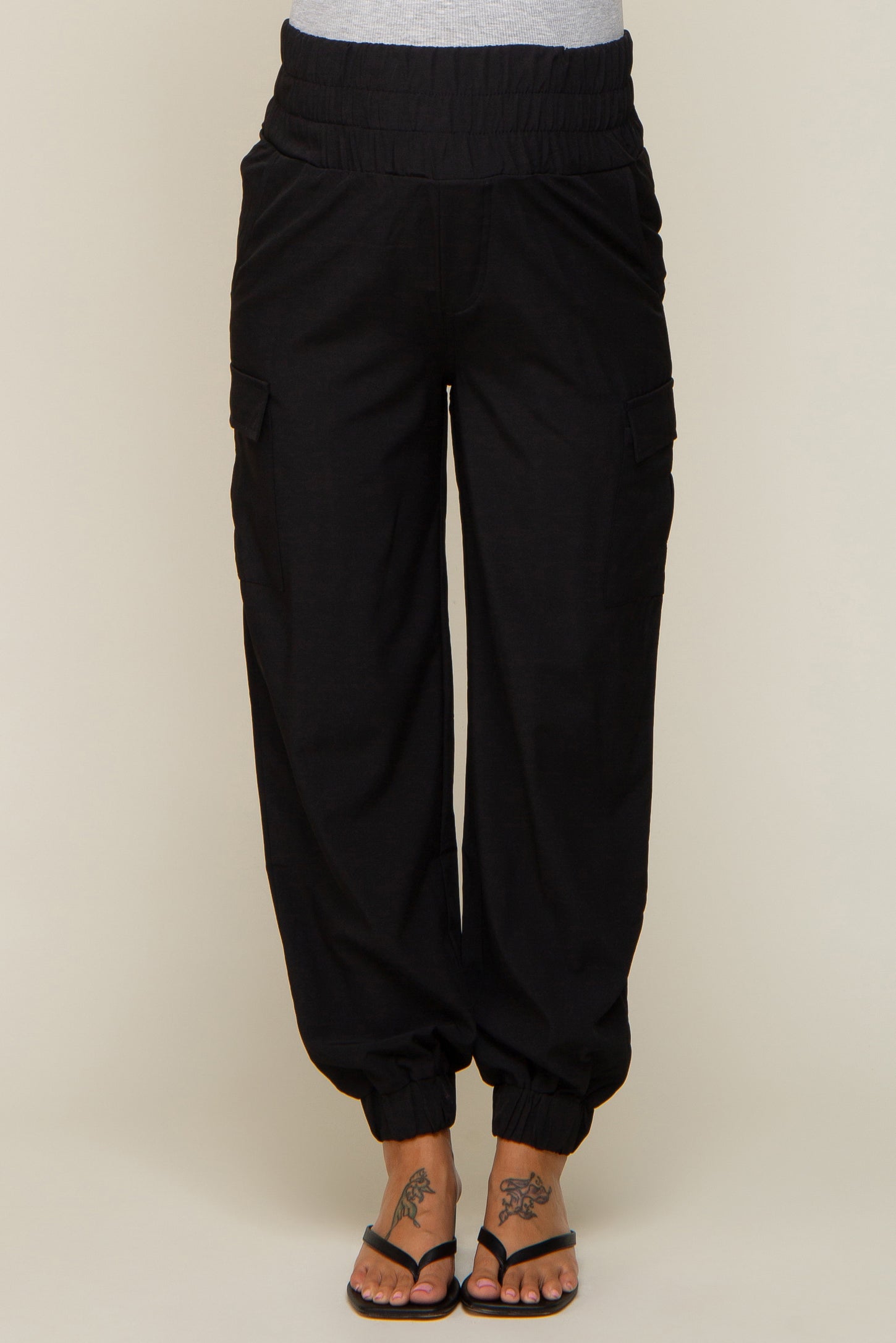 woman wearing black maternity cargo pants with an elastic waistband and tapered ankle cuffs