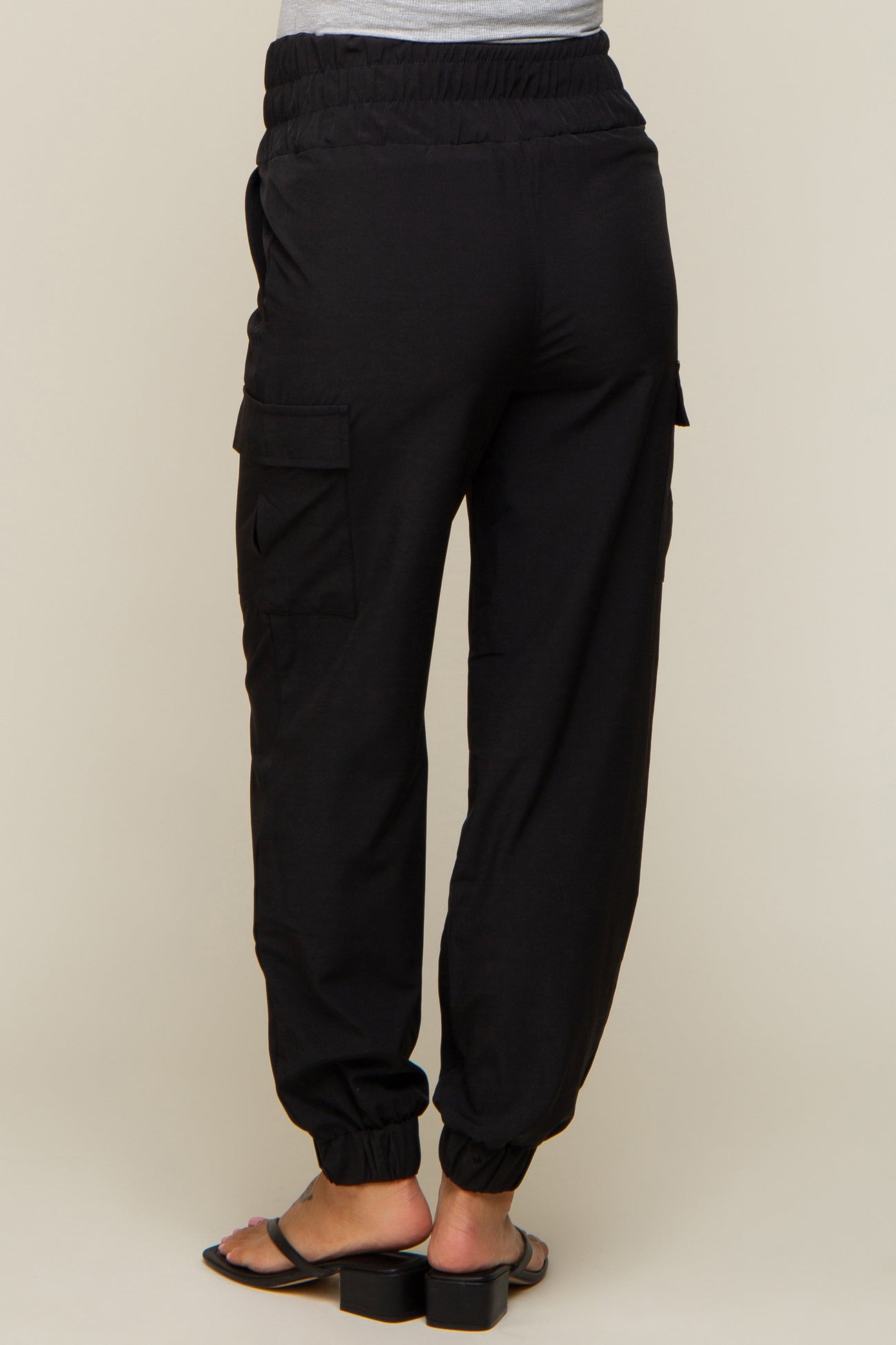 back view of woman wearing black cargo jogger pants with elastic waistband and side pockets