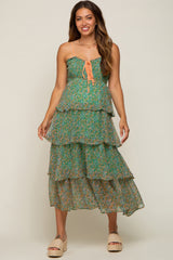 woman wearing a green floral tiered maternity midi dress with orange lace-up bodice and smocked detailing