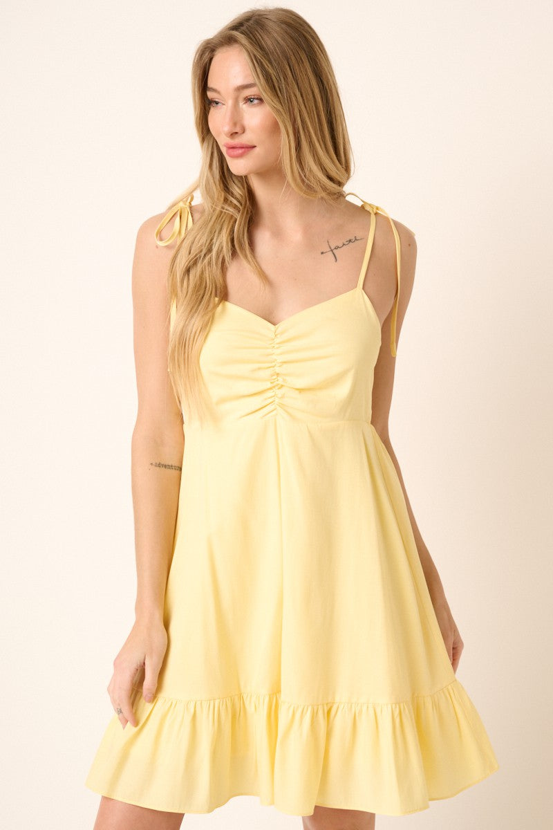 woman wearing a yellow sundress with tie straps and a ruffled hem
