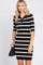 woman wearing a black and white striped short sleeve polo dress with a black shoulder bag