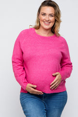 woman wearing a bright pink maternity sweater and holding her baby bump, paired with blue jeans