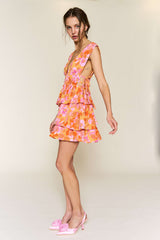 woman wearing an orange floral tiered mini dress with a deep neckline and matching pink heels