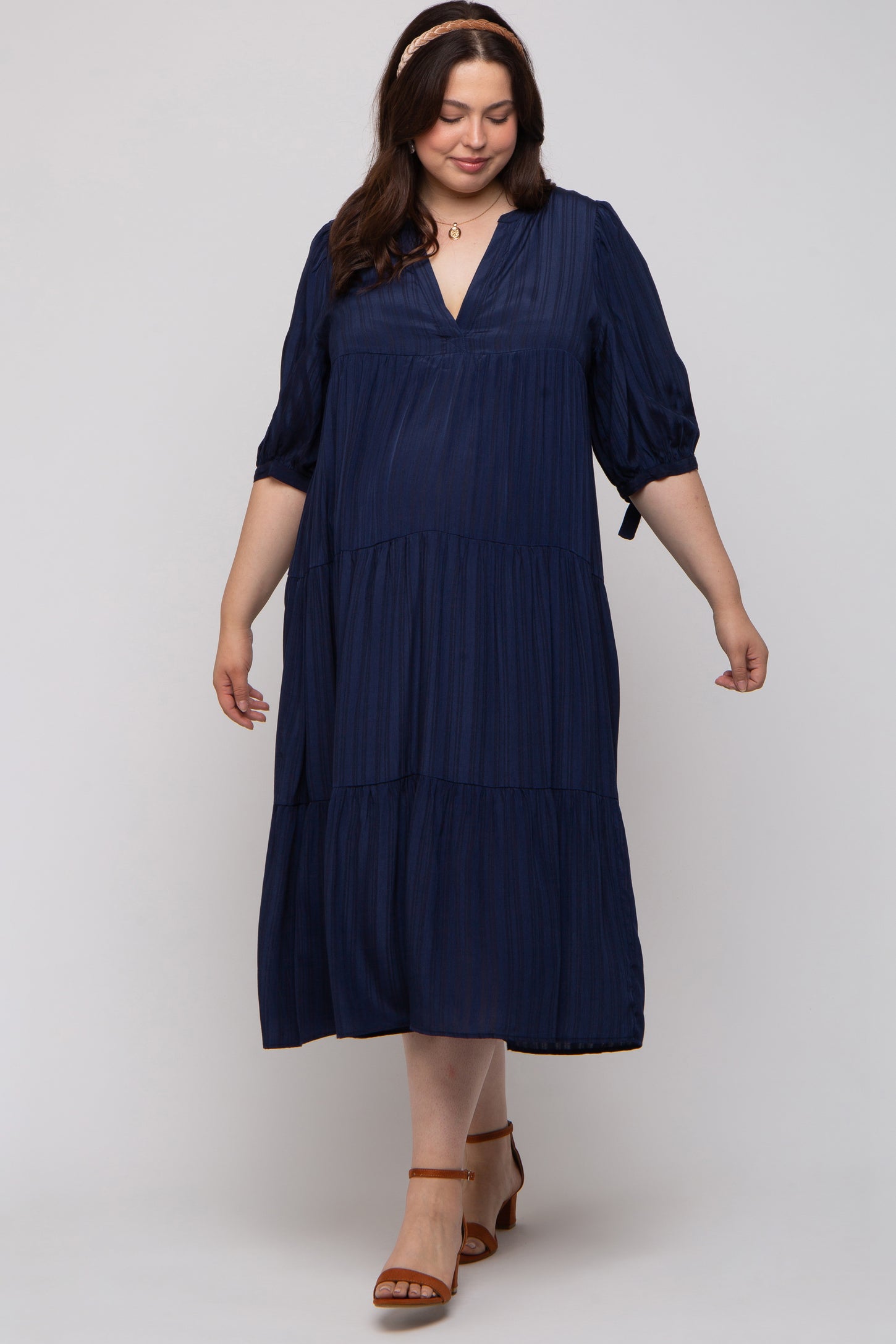 woman wearing a navy blue tiered maternity dress with a deep v-neck and puff sleeves
