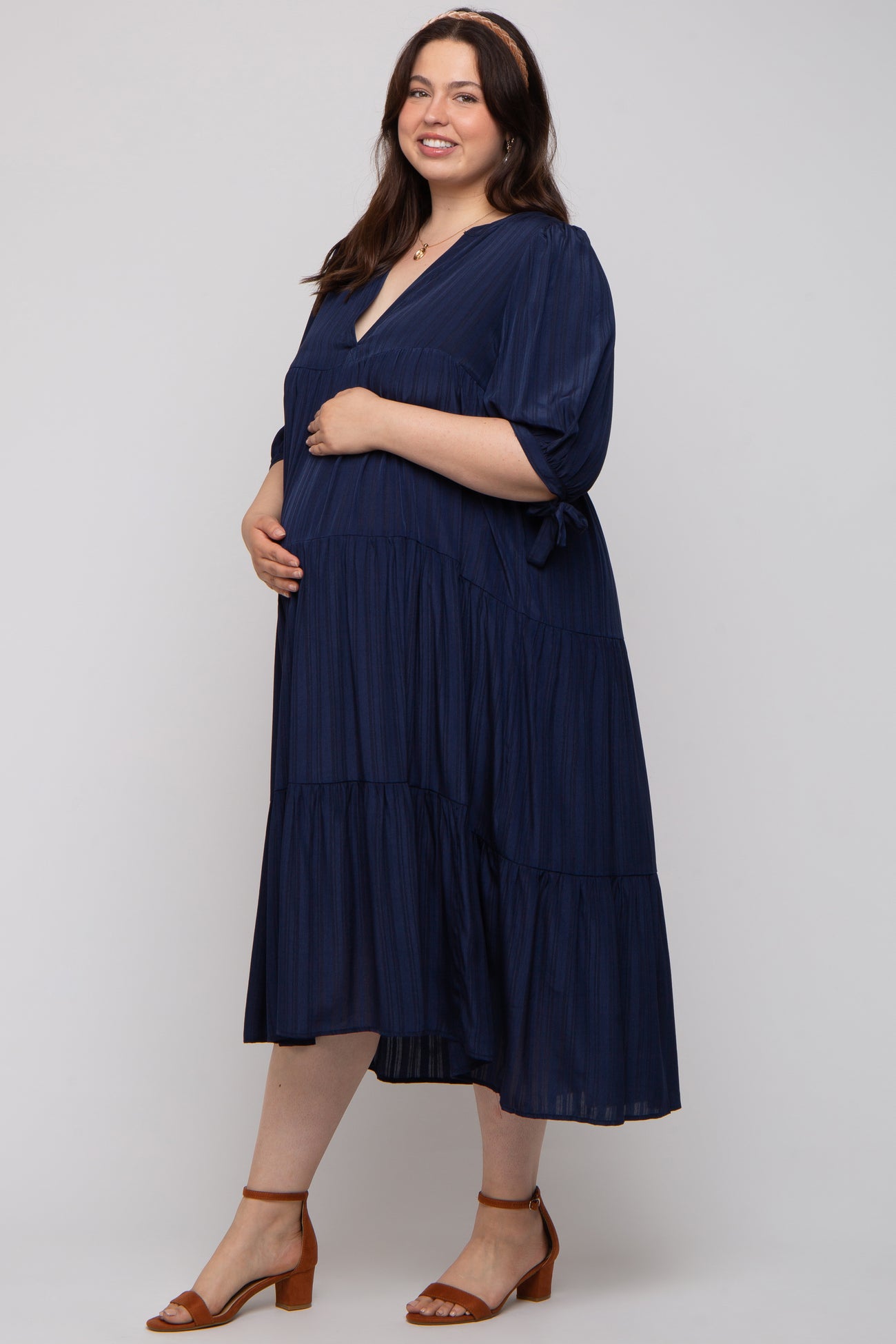 woman wearing a navy blue tiered maternity dress with short sleeves and a visible baby bump