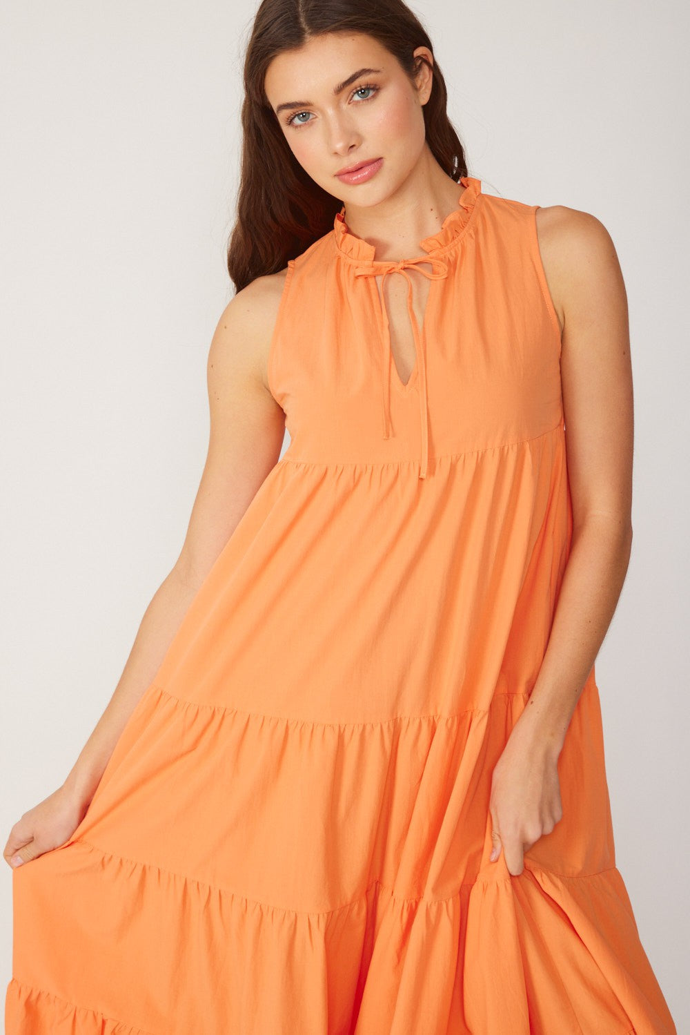 woman wearing an orange sleeveless tiered maxi dress with a ruffled neckline and keyhole detail