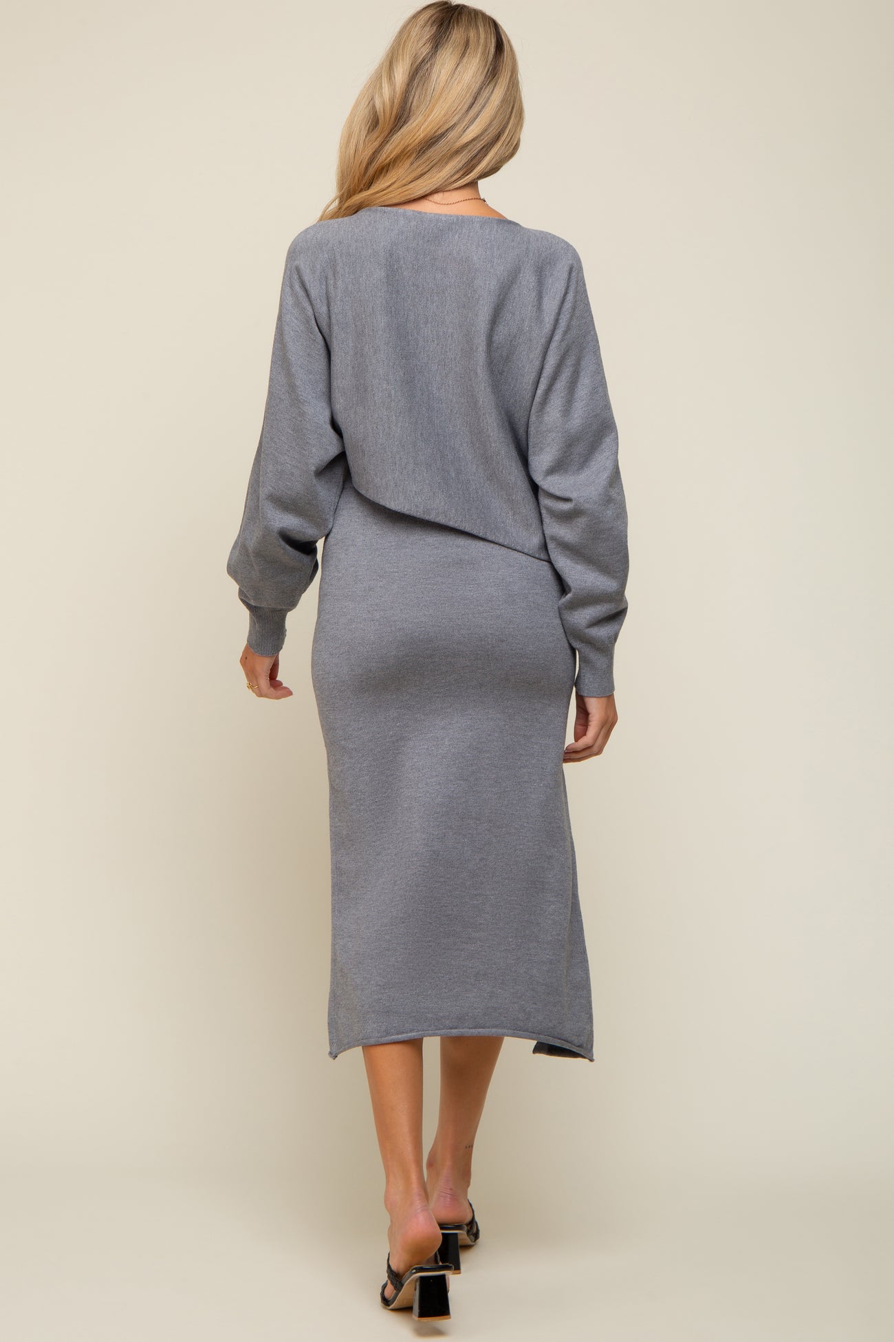 woman wearing a grey maternity sweater dress with long sleeves and a fitted silhouette, displaying a casual look from the back