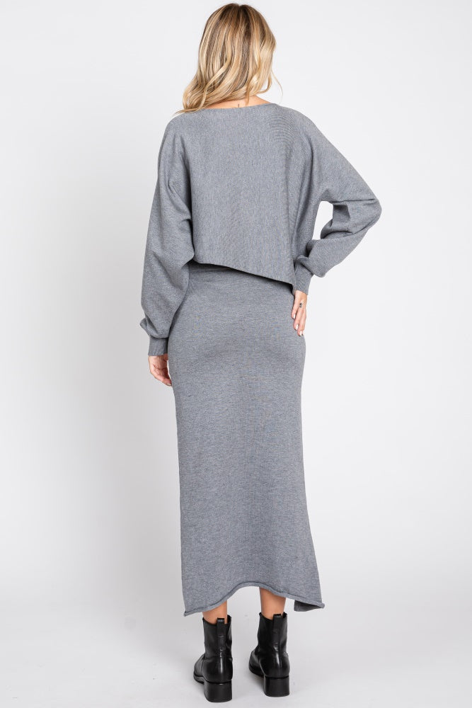 woman wearing a gray cropped sweater and a maxi skirt, viewed from the back