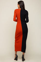 Woman from behind wearing a two-tone orange and black ribbed knit midi dress with long sleeves and black heels