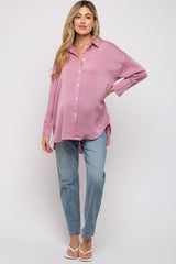 woman wearing a pink ribbed maternity button-up shirt and light blue jeans, with a visible baby bump