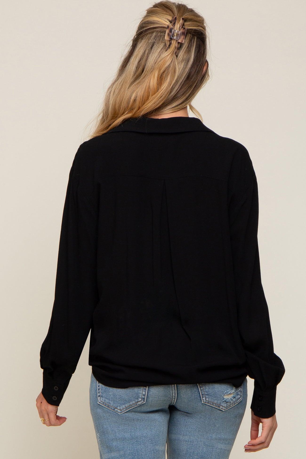 back view of a woman wearing a black long sleeve button down shirt and blue jeans