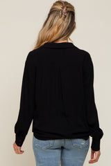back view of a woman wearing a black long sleeve button down shirt and blue jeans