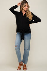 woman wearing a black long sleeve tie-front maternity top and distressed blue jeans