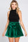 woman wearing a black sleeveless top and green velvet high-waisted shorts with a tied waist detail