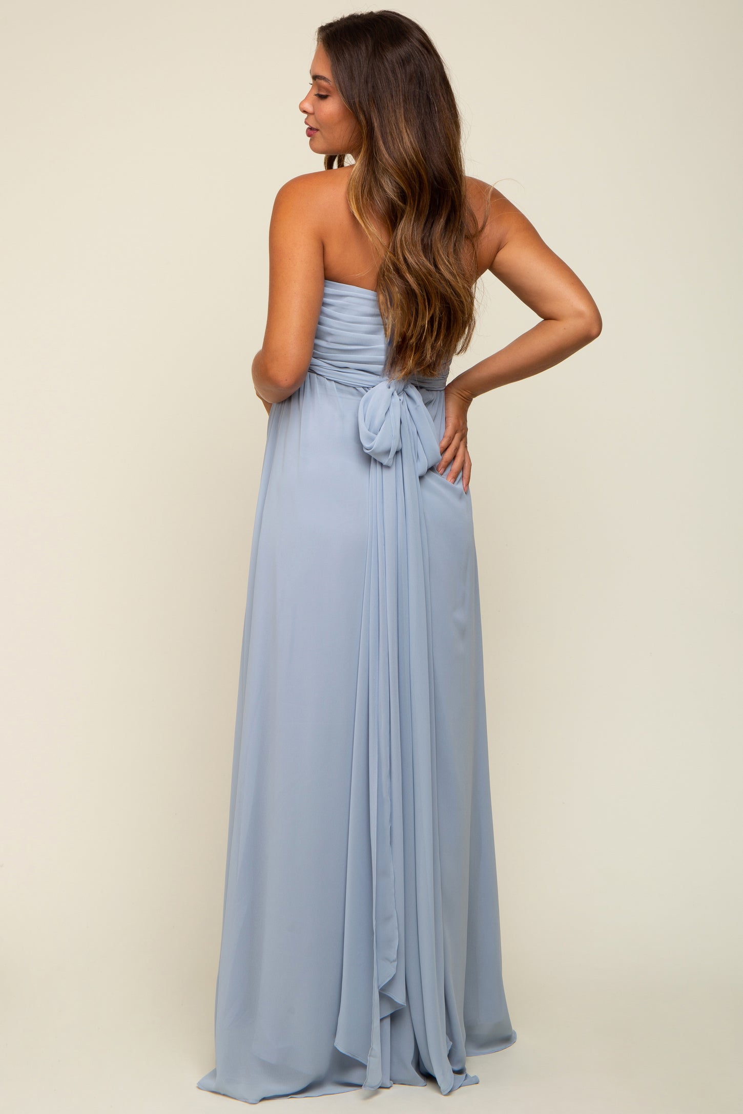 woman wearing a light blue strapless maternity gown with a tie detail at the back