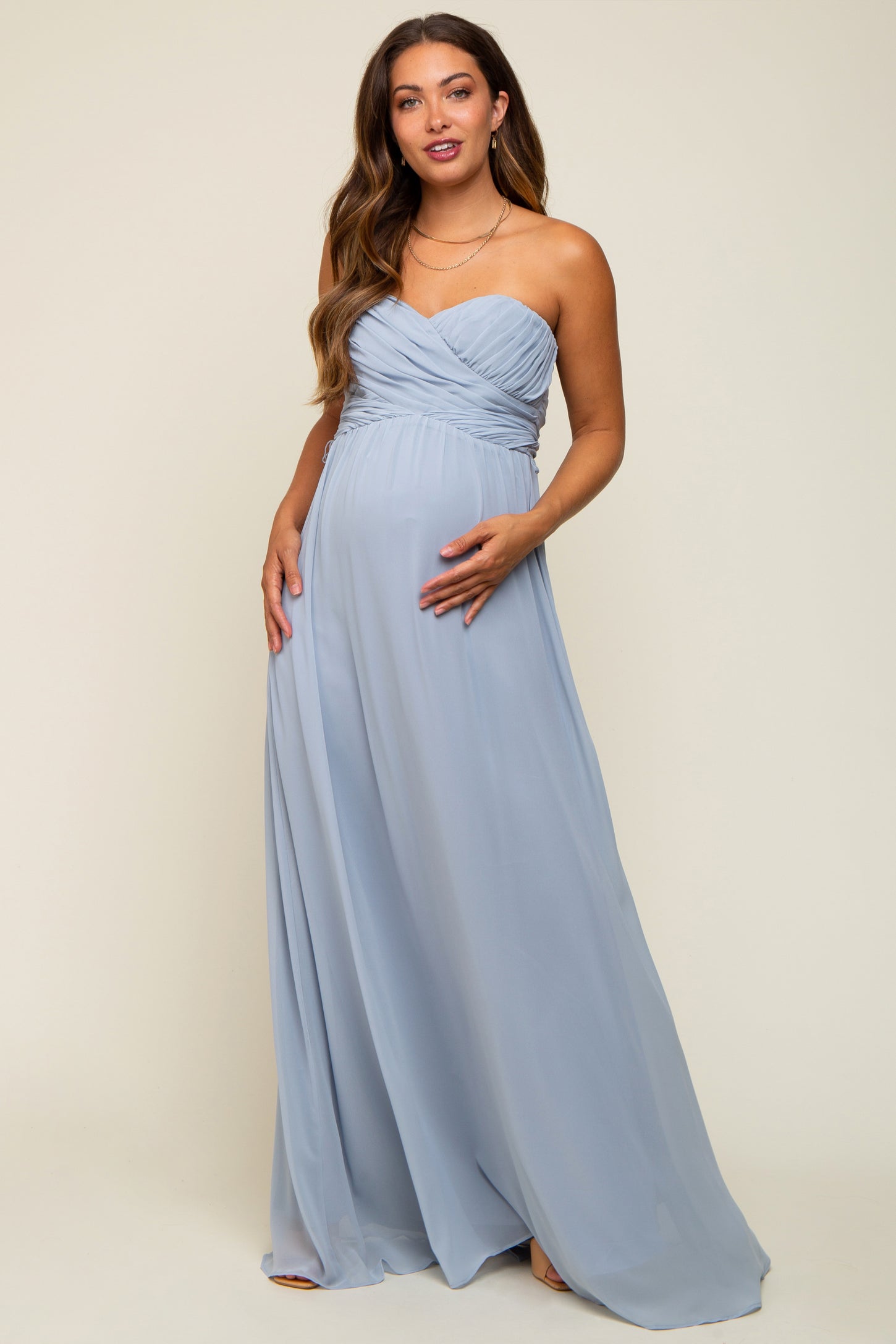 woman wearing a light blue strapless maternity gown with a ruched bodice and a visible baby bump