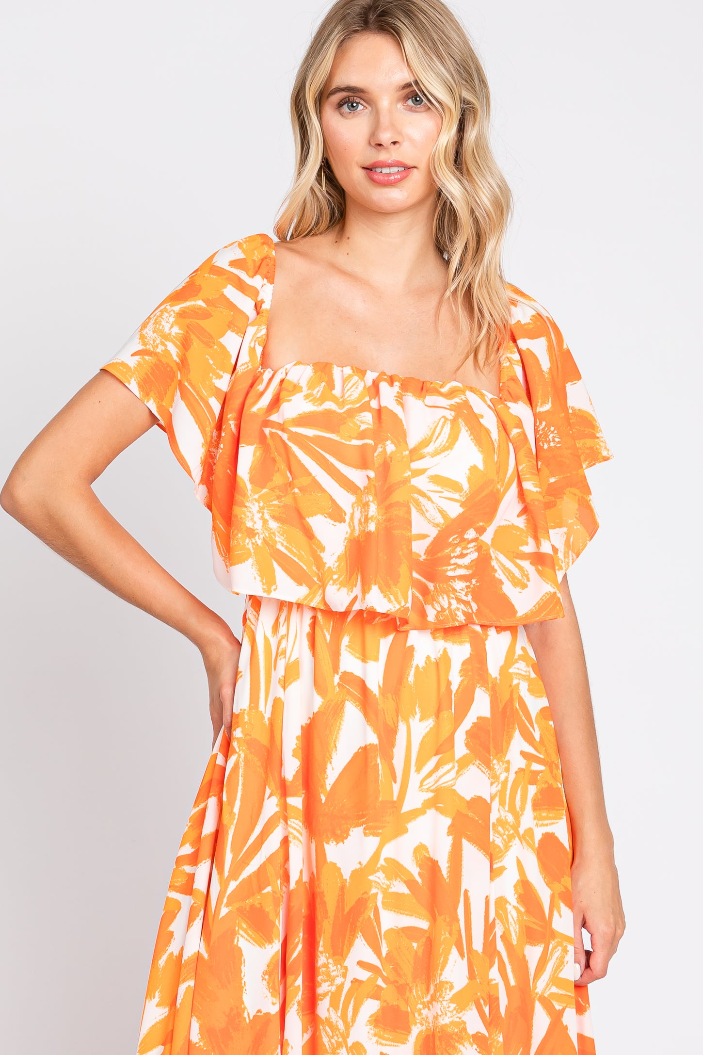 woman wearing a square neck orange floral print maxi dress with ruffled short sleeves