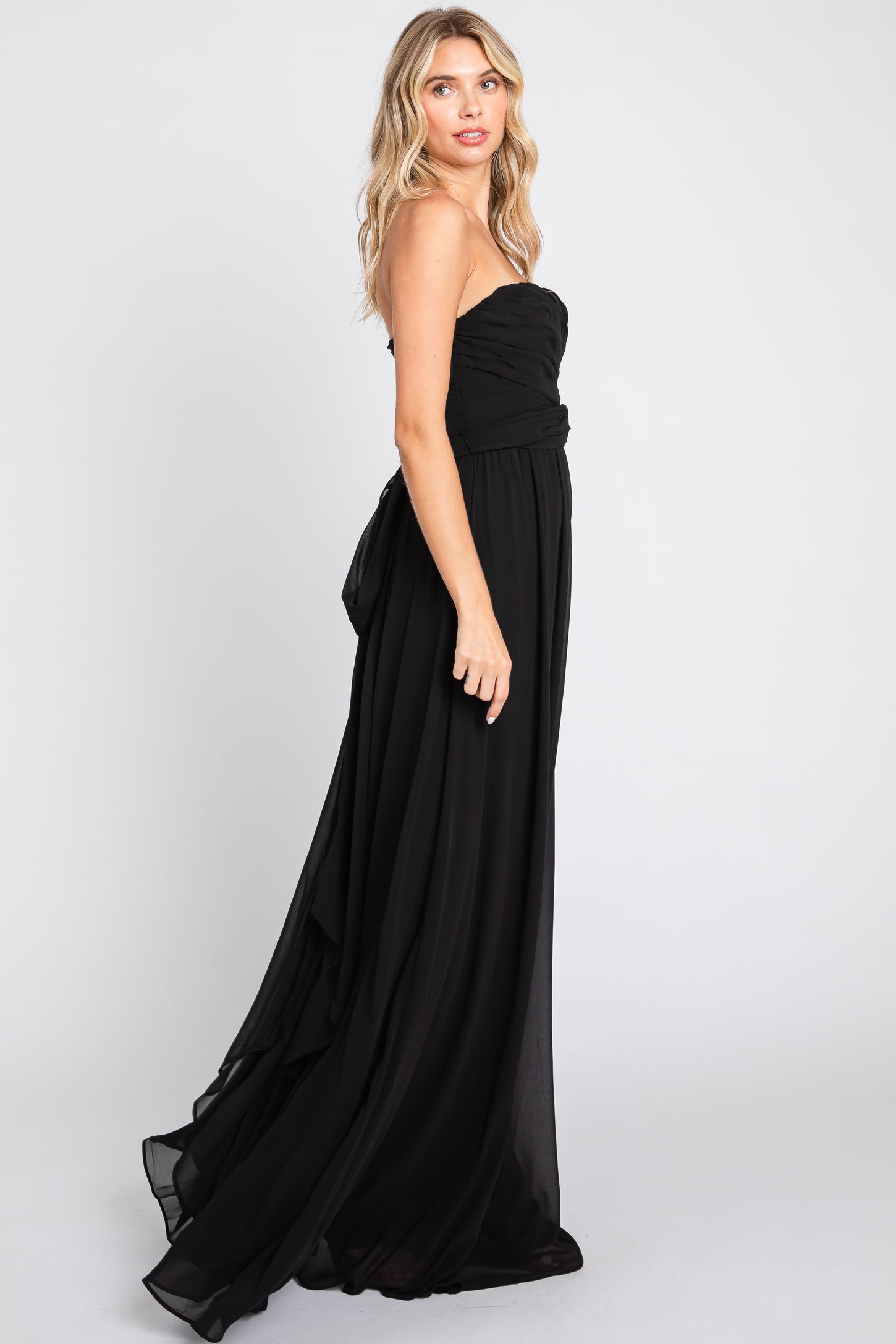 woman wearing a strapless black evening gown with a ruched bodice and a flowing skirt