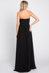 woman wearing a black strapless maxi dress with a tied bow detail at the back