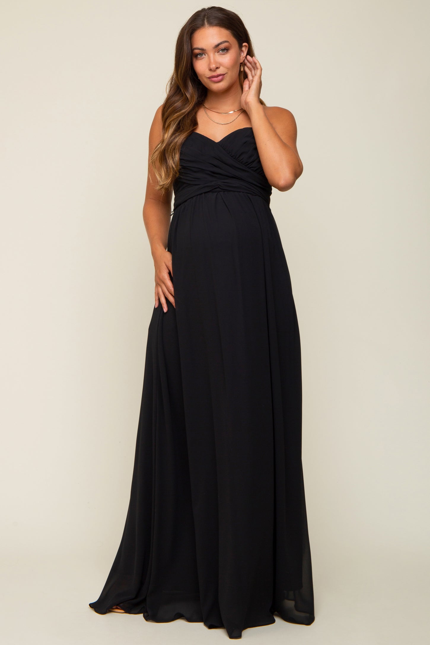 woman wearing a black strapless maternity gown with gathered detailing and a visible baby bump