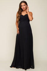 woman wearing a black strapless maternity gown with gathered detailing and a visible baby bump