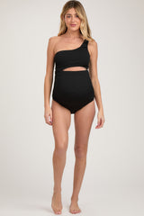 woman wearing a black one-shoulder maternity swimsuit with a cut-out detail, highlighting her baby bump