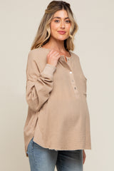 woman wearing a beige long sleeve maternity top with buttons and side slits, showcasing her baby bump