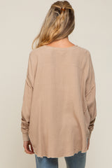 woman wearing a loose beige maternity top with long sleeves and a relaxed fit, seen from the back