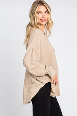 woman wearing a beige oversized long sleeve top with raw edges and a relaxed fit