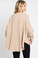 woman wearing a beige oversized long sleeve top with a relaxed fit and textured fabric, seen from the back