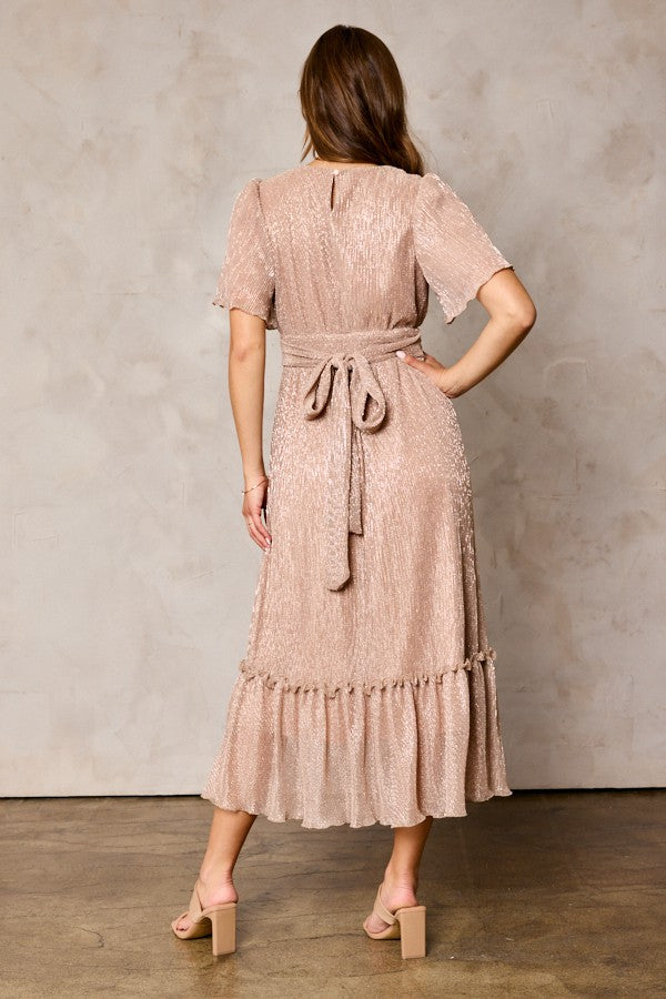 woman wearing a light taupe midi dress with short sleeves and a tie waist, back view, with ruffle hem and textured fabric
