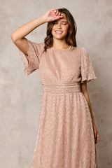 woman wearing a shimmer pink short sleeve evening dress with a cinched waist and flowy skirt