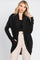 Woman wearing a long black ribbed cardigan over a black top and beige trousers