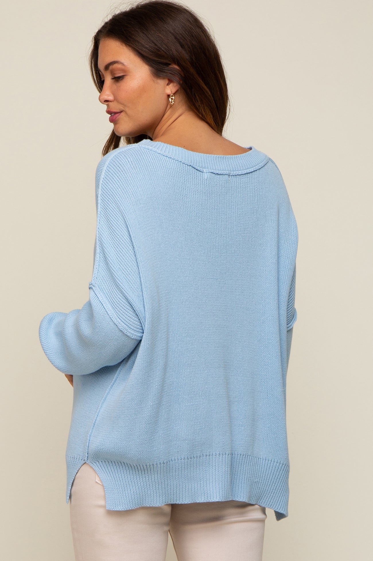woman wearing a light blue oversized maternity sweater with a relaxed fit and side slits