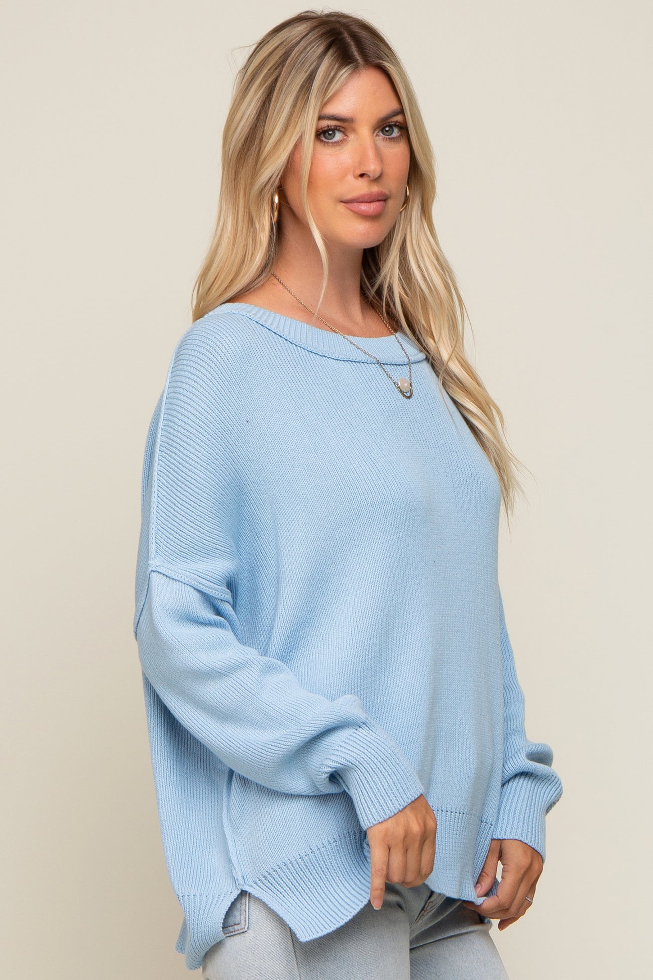 woman wearing a light blue oversized knit sweater with dropped shoulders and long sleeves