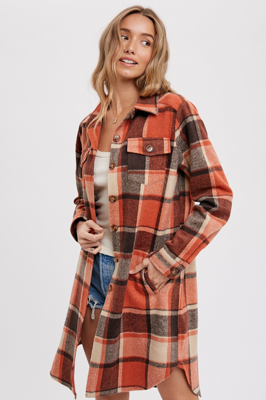 woman wearing an orange and brown plaid button-up shirt jacket paired with shorts