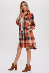 woman wearing an orange and brown plaid shirt dress with long sleeves and pockets, paired with brown heeled ankle boots
