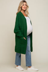 pregnant woman wearing a long green waffle knit maternity cardigan with white top and blue jeans
