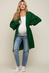 pregnant woman wearing a long green waffle knit maternity cardigan with white top and distressed jeans