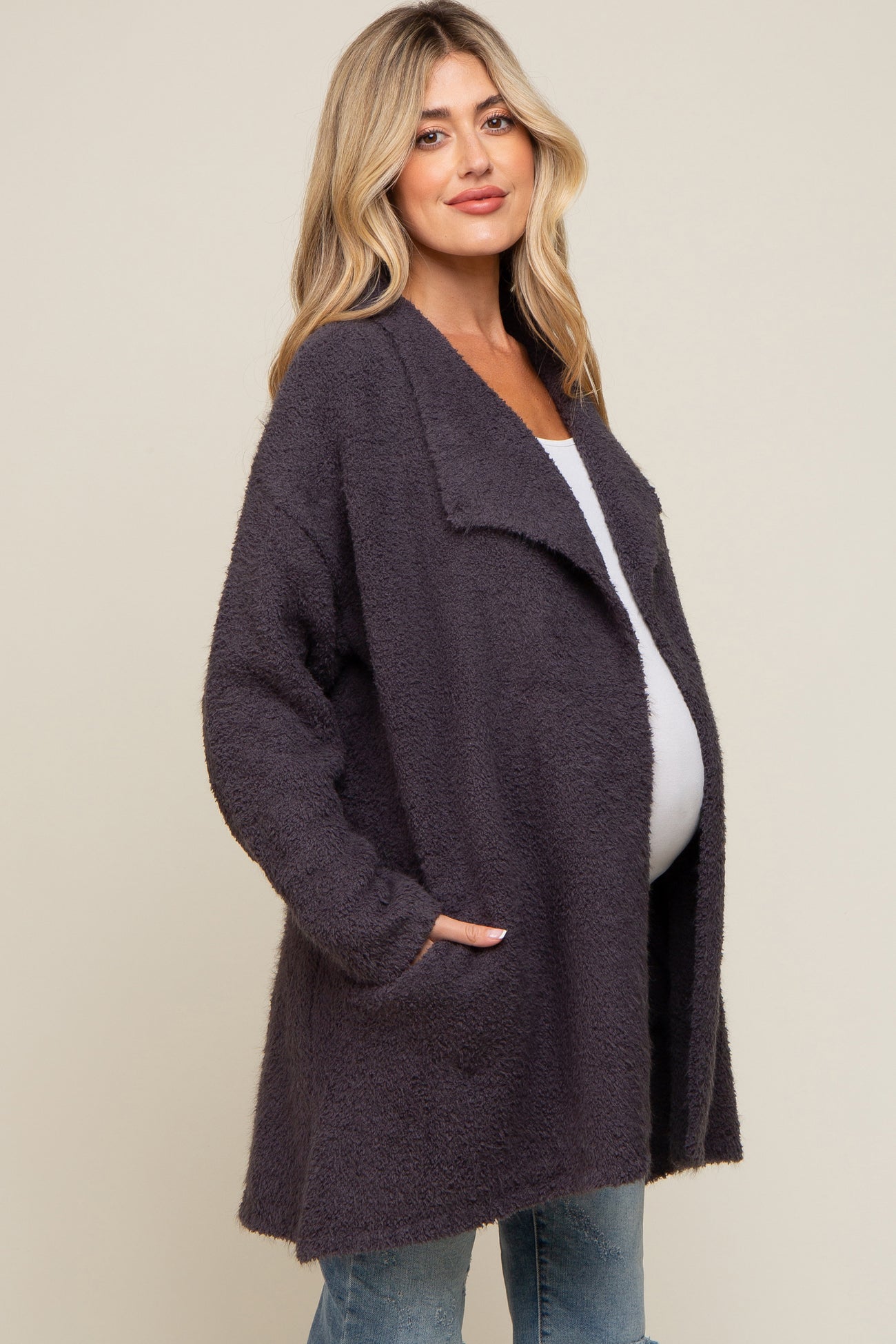 pregnant woman wearing a charcoal grey fuzzy maternity cardigan over a white top and jeans