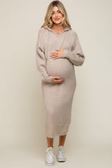 woman wearing a beige maternity hoodie dress and holding her baby bump