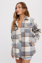 woman wearing a plaid button-up shacket in gray, cream, and brown with front pockets and rolled sleeves