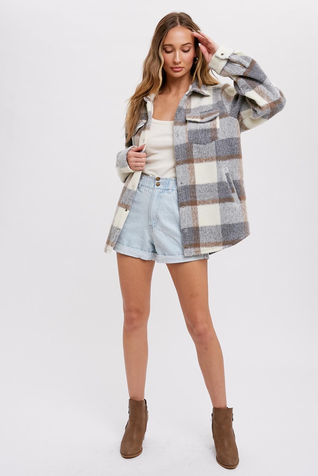 woman wearing a checkered gray and cream shacket paired with light denim shorts and ankle boots