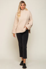 Woman wearing a beige oversized ribbed turtleneck sweater and black cropped jeans with loafers