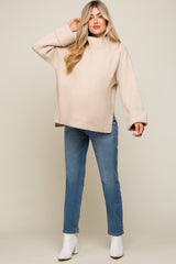 woman wearing oversized beige turtleneck ribbed sweater with blue jeans and white boots
