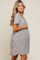 Pregnant woman wearing a blue floral maternity dress with short sleeves and a tiered skirt