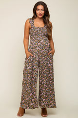 woman wearing a floral maternity jumpsuit with wide legs and pockets, featuring a square neckline and ruffled straps