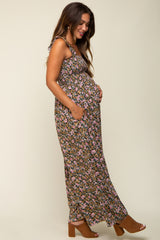 woman wearing a black floral maternity maxi dress and holding her baby bump